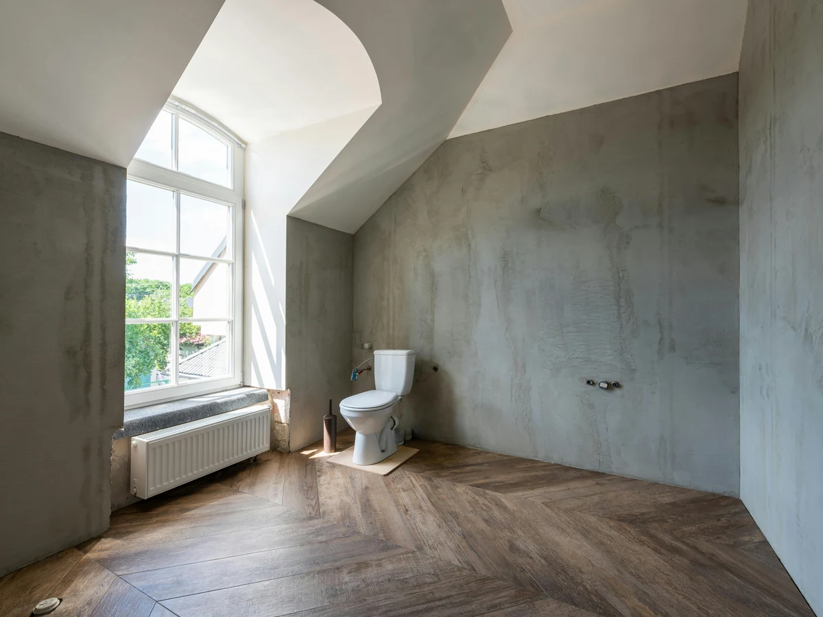 Bathroom with bare concrete walls being prepared for painting by Richmond Decorators