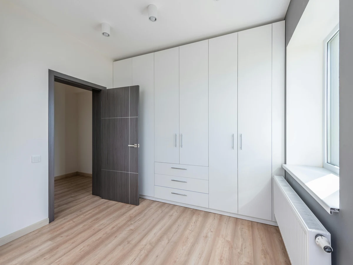 bedroom-painting-clean-white-bedroom-richmond-decorators A clean white bedroom with built-in wardrobes and a radiator under the window