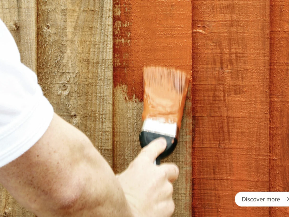 Decorator applying stain to a timber fence in Richmond upon Thames