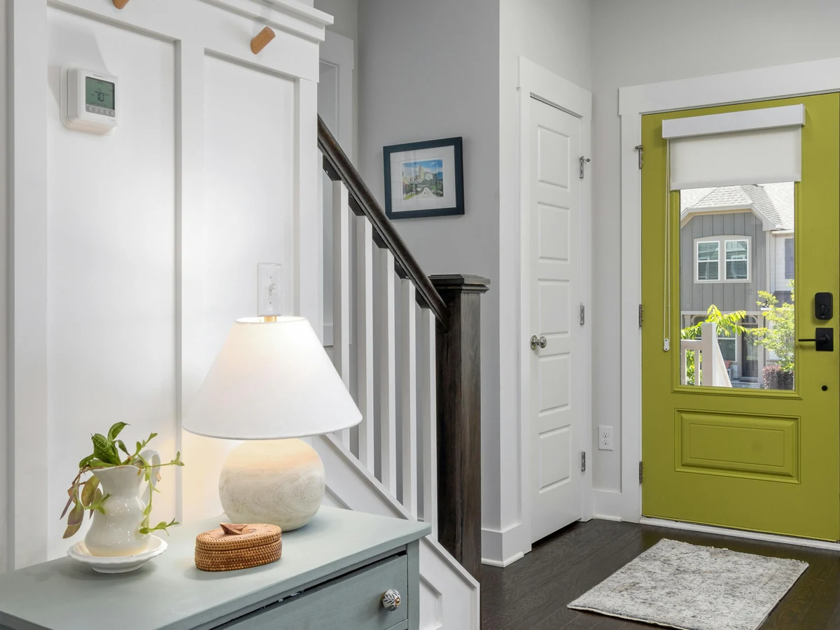 hallway-painting-hallway-entrance-bright-richmond-decorators Light grey hallway with a gilt mirror, a lamp on a side table and a white front door