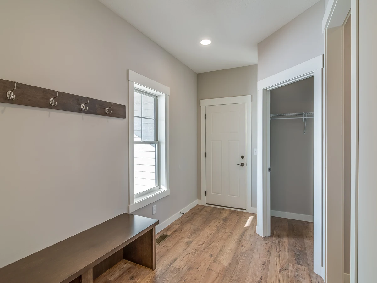 hallway-painting-new-build-mudroom-richmond-decorators A new-build hallway with pale walls, a coat rail, a bench and a white door