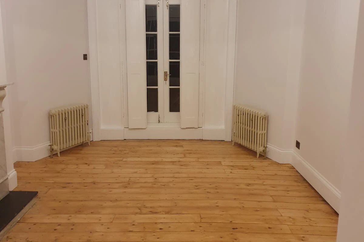 interior-painting-richmond-richmond-decorators Empty period room with tall glazed doors, cast iron radiators and a bare wooden floor