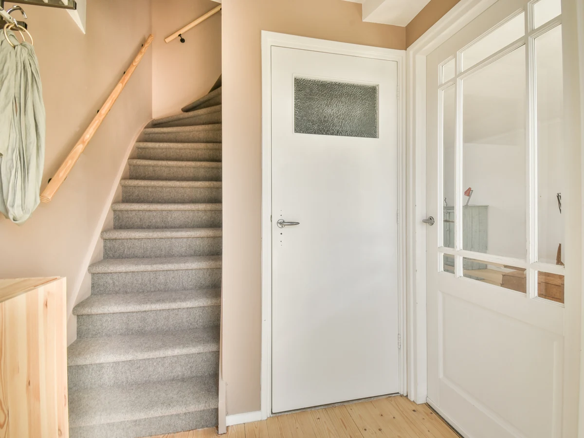 Bright carpeted hallway with freshly painted staircase and white woodwork by Richmond Decorators