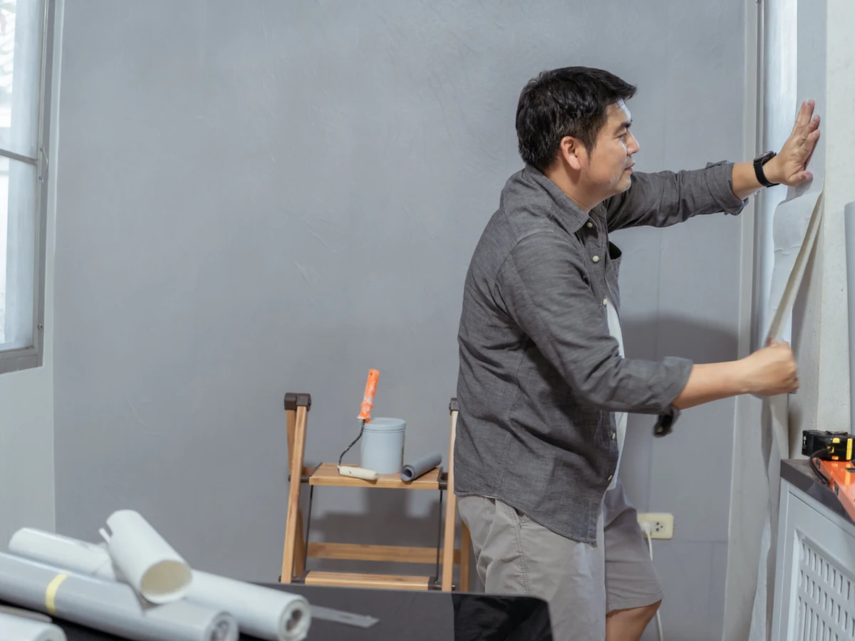 wallpapering-man-applying-wallpaper-richmond-decorators Wallpaper installer hanging wallpaper in a Richmond property — Richmond Decorators